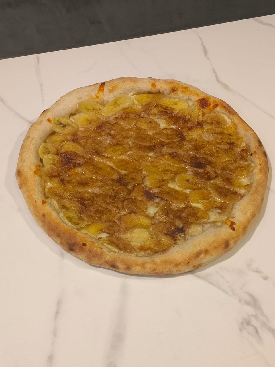 Banana com Canela — Massa de fermentação natural, banana caramelizada, canela e açúcar mascavo.